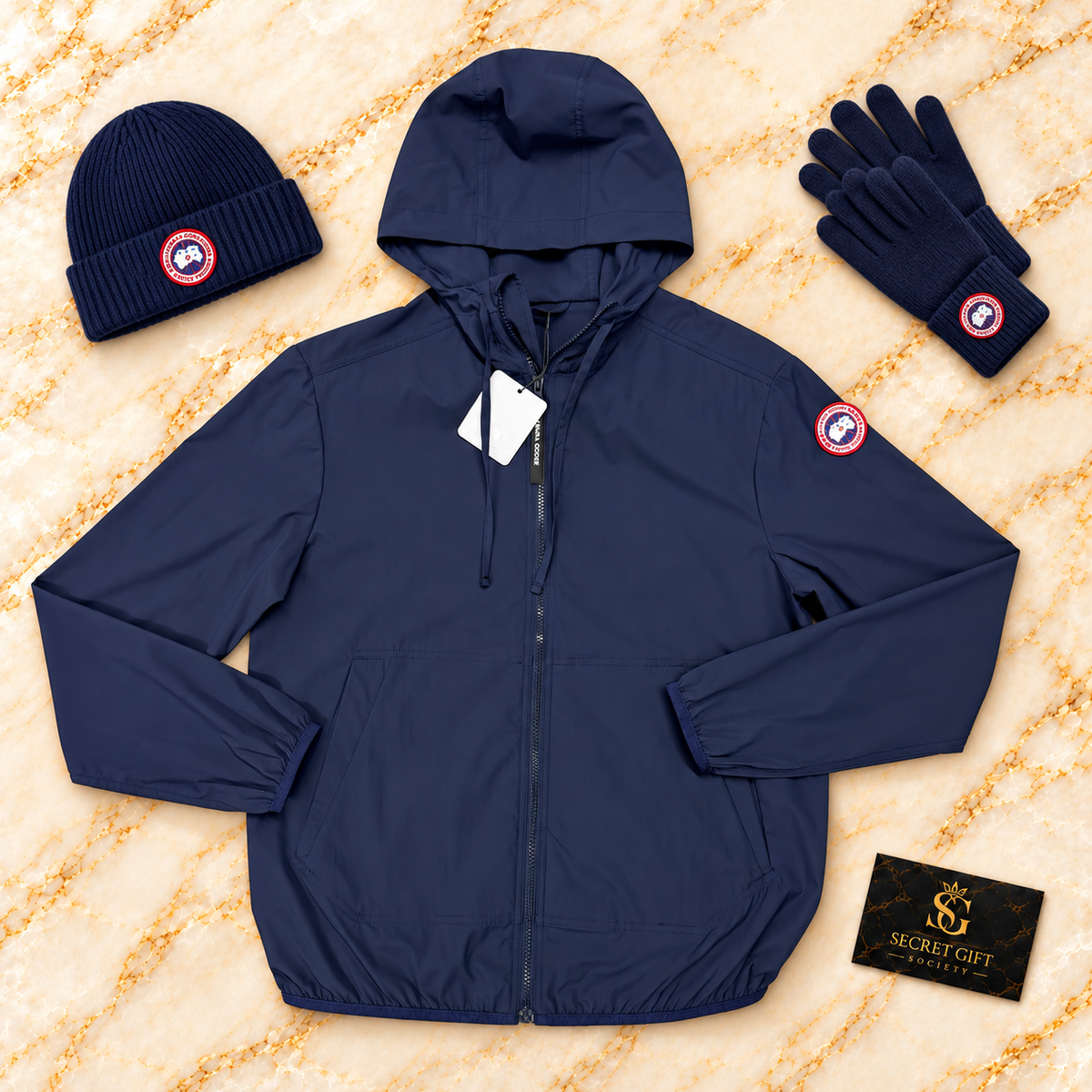 Navy Canada Goose Killarney wind jacket on ivory marble with Secret Gift Society card; hat and gloves are styling props