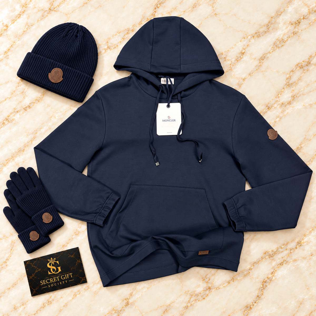MNCLR LEATHER LOGO HOODIE - NAVY on ivory marble with matching branded beanie and gloves and Secret Gift Society business card