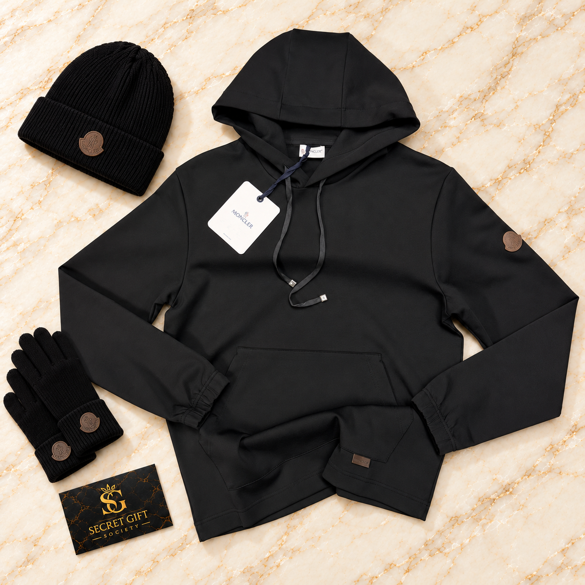 MNCLR LEATHER LOGO HOODIE - BLACK on ivory marble with matching branded beanie and gloves and Secret Gift Society business card