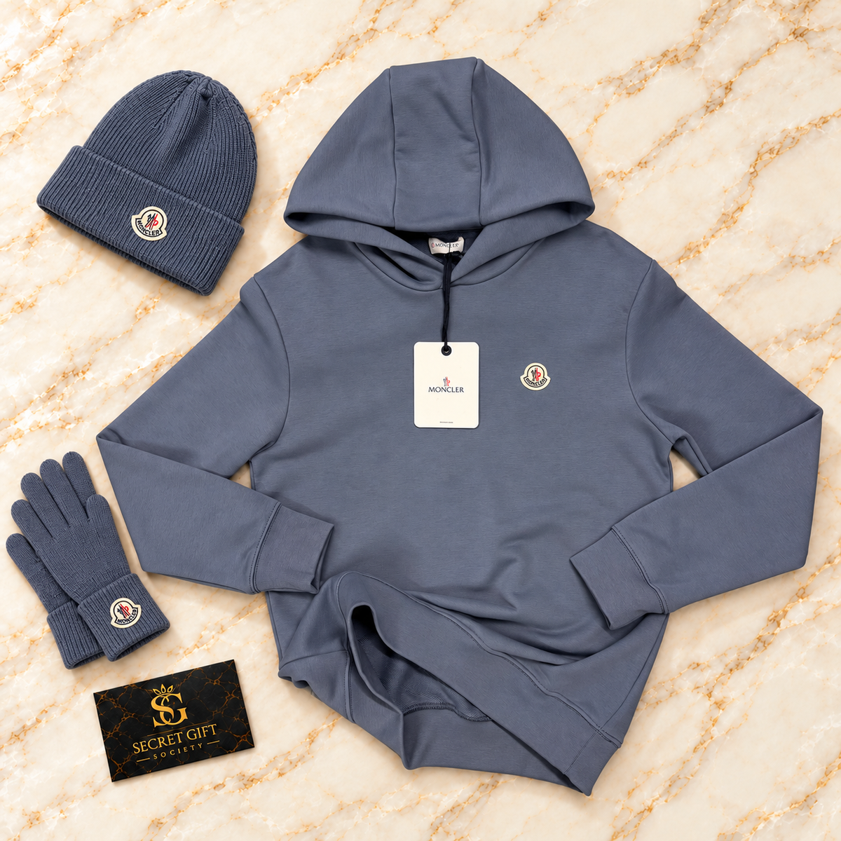 MNCLR LOGO HOODIE - PALE BLUE on ivory marble with matching branded beanie and gloves and Secret Gift Society business card