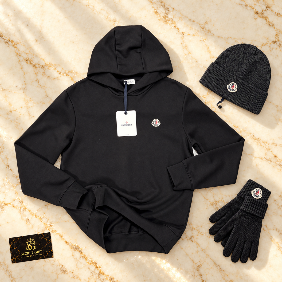 MNCLR LOGO HOODIE - BLACK on ivory marble with matching branded beanie and gloves and Secret Gift Society business card